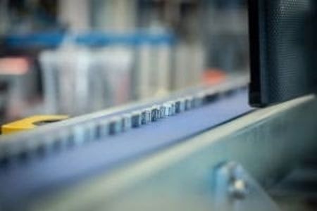 Nahaufnahme eines Förderbands mit kleinen, beschrifteten Artikeln