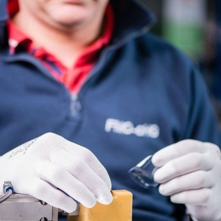 Person mit weißen Handschuhen hält einen kleinen Glasbehälter